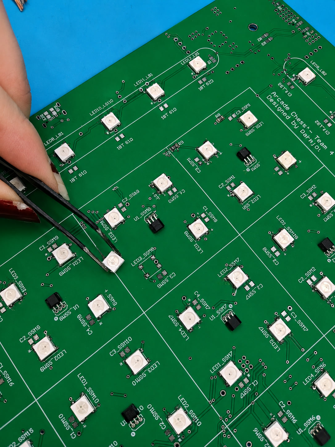 Placing a surface-mount LED on a green PCB with tweezers