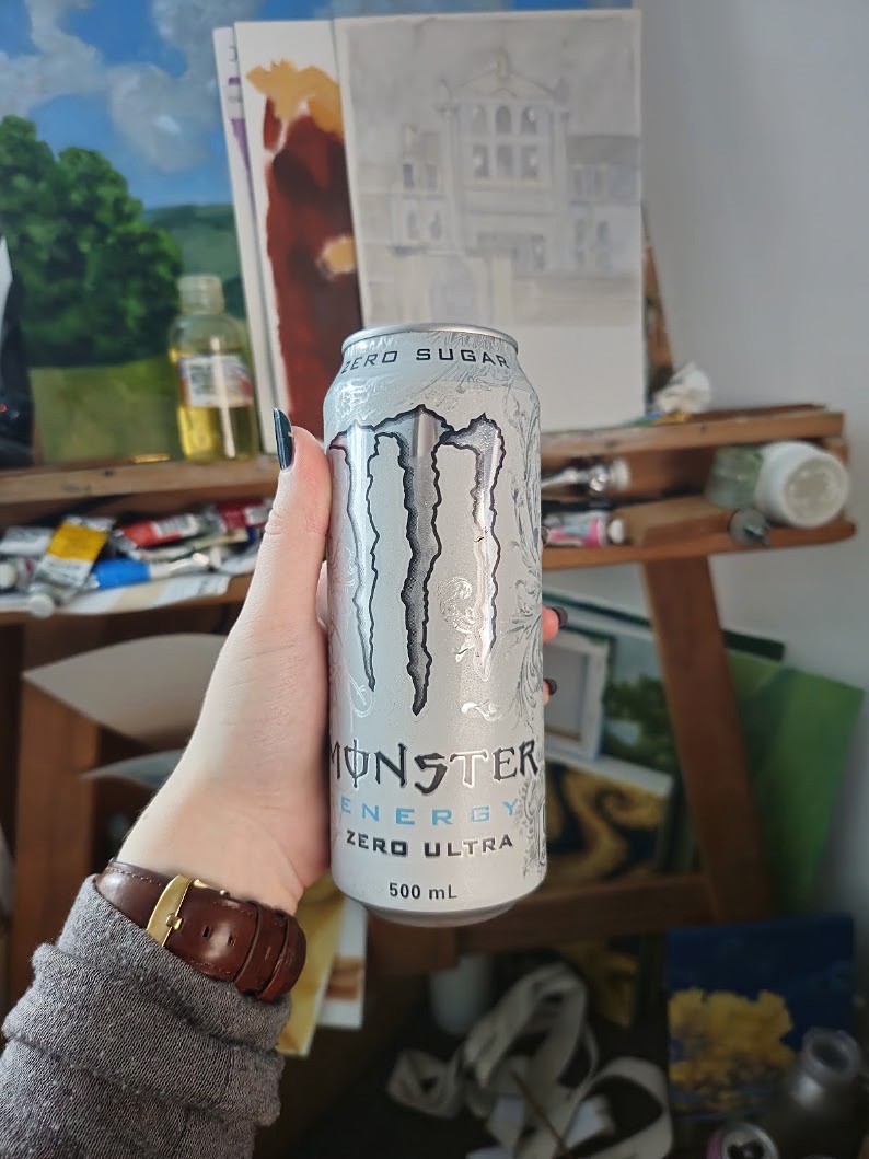 Ara holding a can of Monster Zero Ultra in front of the paint shelf